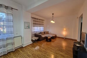 A living room with a sofa, a small table, and a TV. - Spacious Apartment In The Centre Of The Capital (Bucharest)