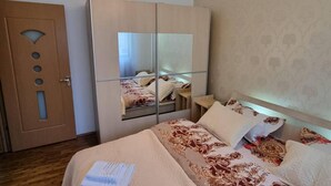 Ett hotellrum med en stor spegel, en säng med mönstrat sänglinne, en trädörr och en vägg med mönster.