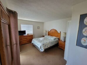 A bedroom with a bed, bedside tables, a dresser, a television, and a window with blinds. - I had to cancel my condo rental - You reap the Benefit of a DEEP DISCOUNT (Rodanthe)