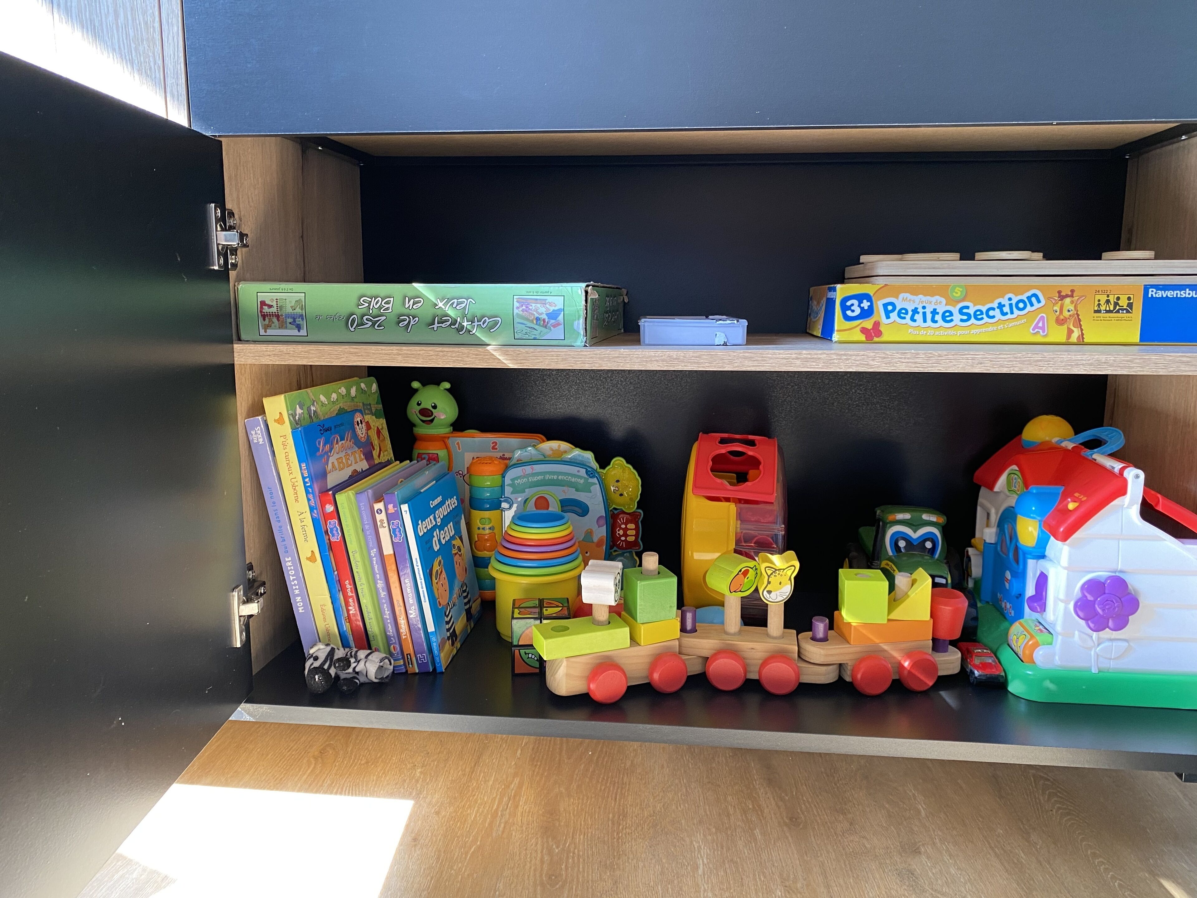 Un cajón con juguetes infantiles, libros y un tren de juguete.