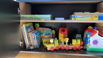 Un cajón con juguetes infantiles, libros y un tren de juguete.