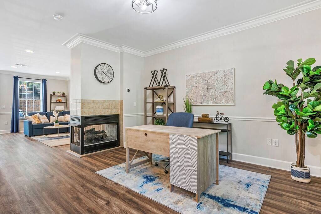 A modern living room with a fireplace, a desk, and a large plant.