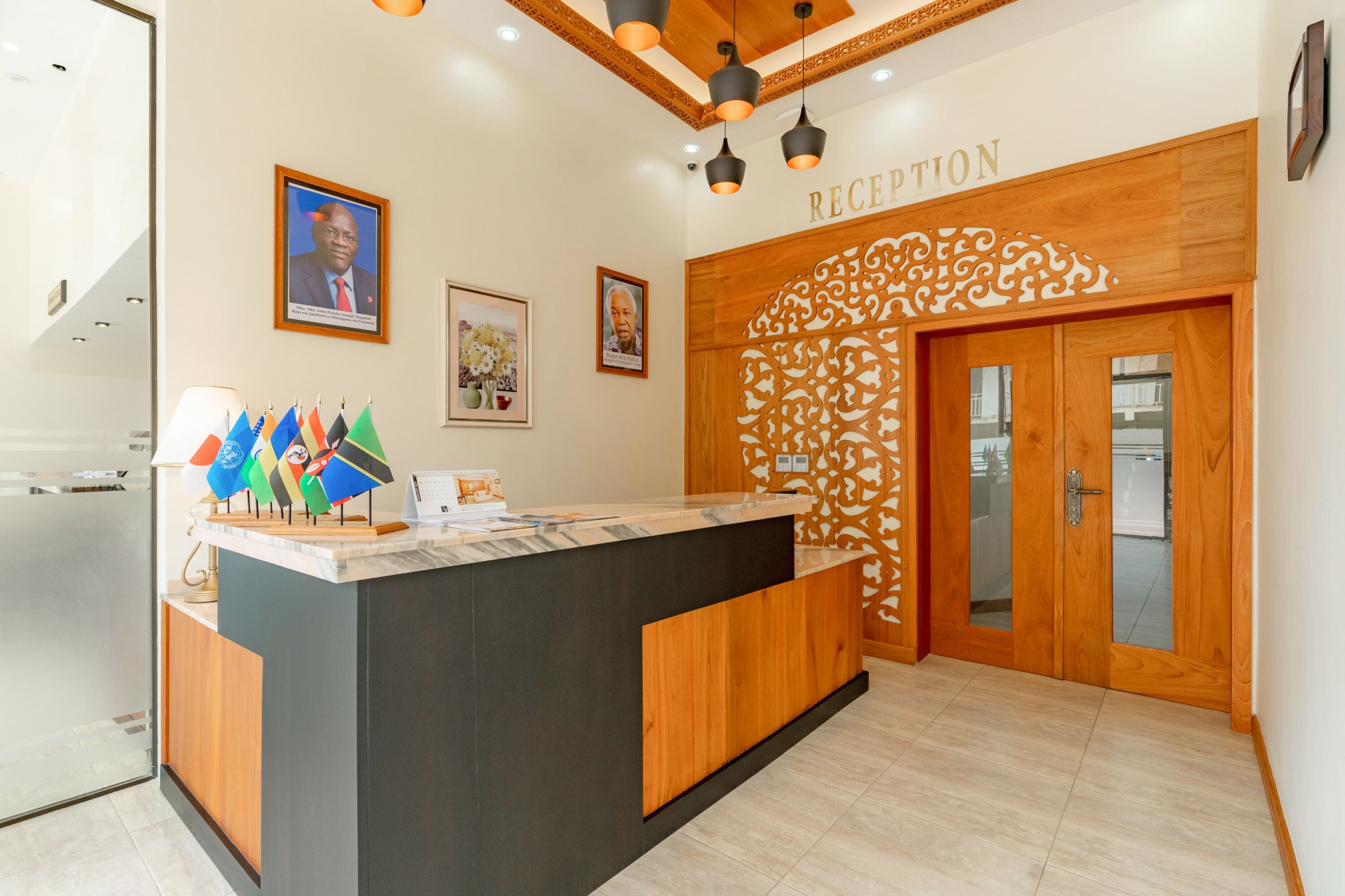 A reception area with a wooden reception desk, a 'RECEPTION' sign, and flags on the wall.