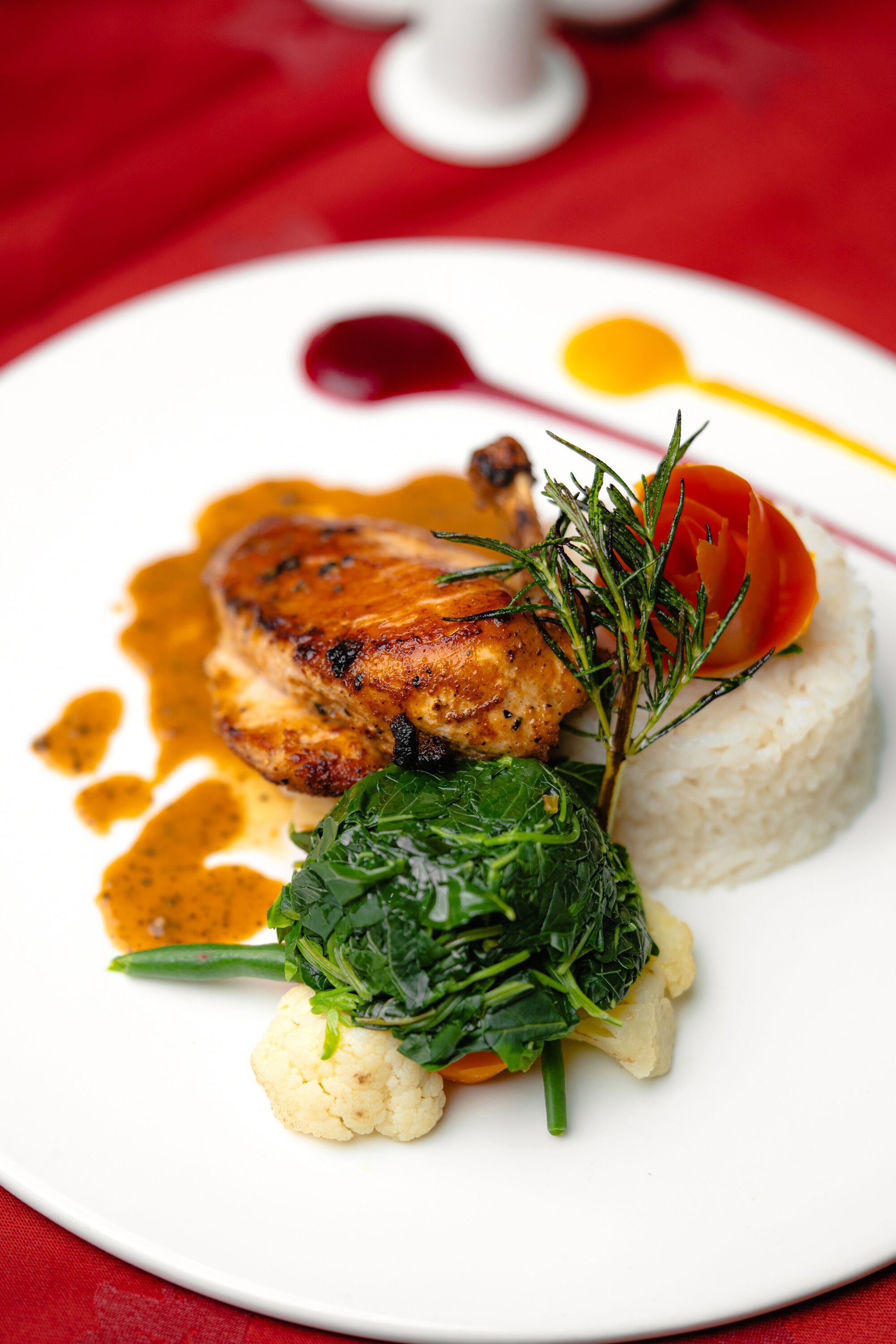 Une assiette de nourriture comprenant un morceau de poulet grillé, une portion de riz et des légumes.