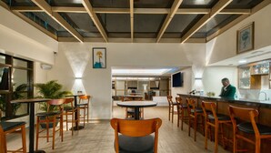 A spacious restaurant with wooden chairs and tables, a bar area, and a modern ceiling design. - Kibo Palace Hotel Moshi (Moshi)