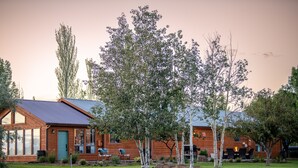 A wooden cabin with a blue roof, surrounded by a grassy yard and trees.