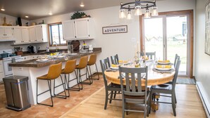 A modern kitchen with white cabinets, a central island, and a dining area with a round table and chairs.