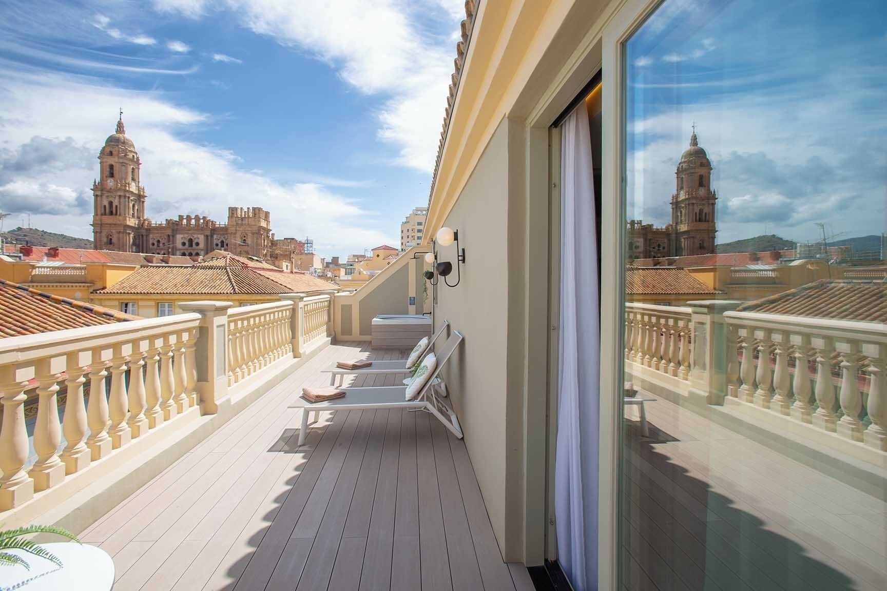 Un balcón con vistas a edificios históricos, una puerta de cristal y una barandilla.