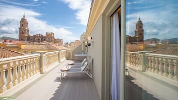 Un balcón con vistas a edificios históricos, una puerta de cristal y una barandilla.