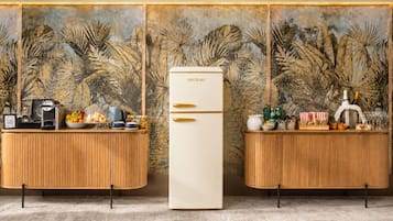 A modern kitchen with two wooden counters, a white refrigerator, and a tropical leaf-patterned wall.