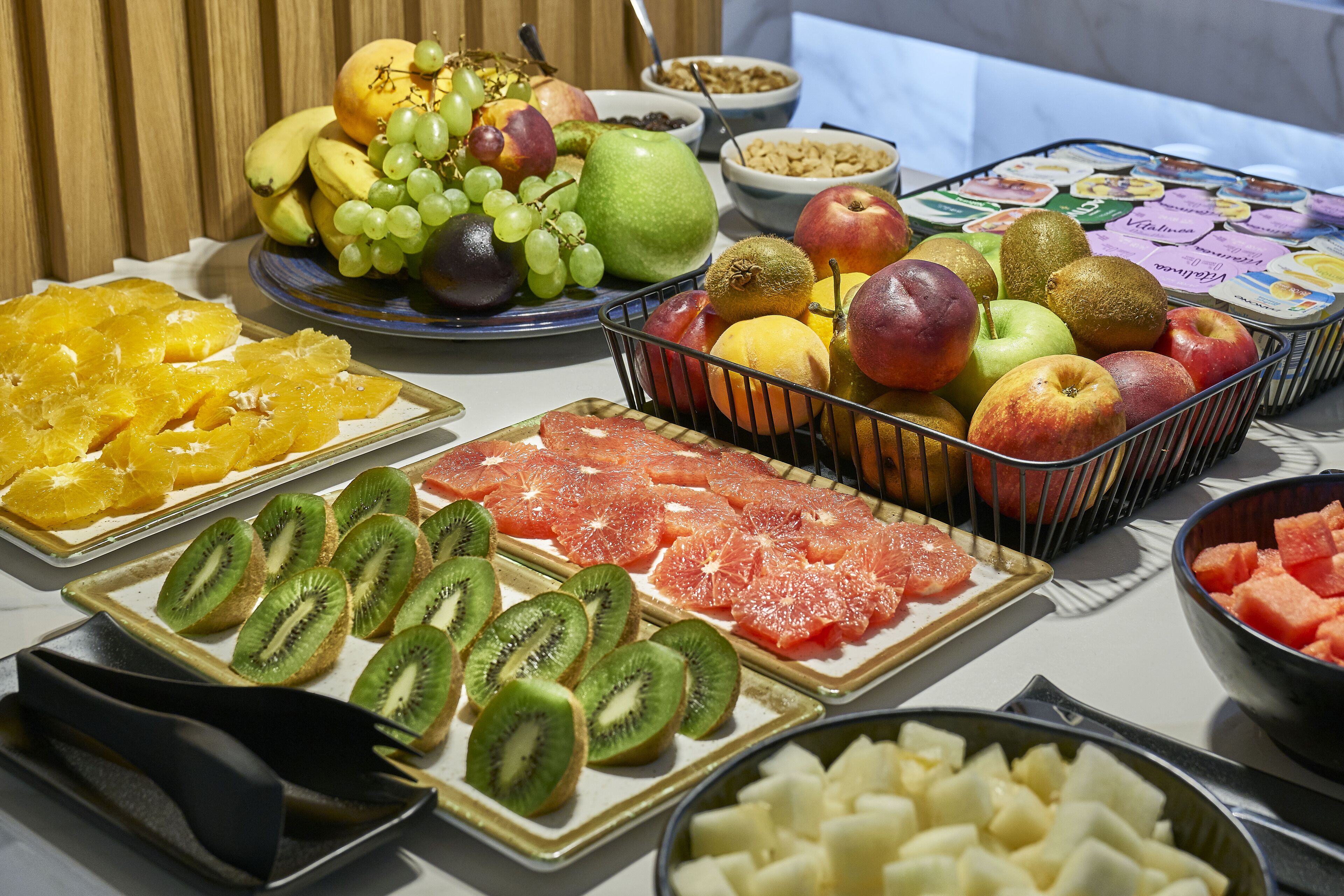 Une variété de fruits et de légumes disposés sur une table, notamment des kiwis, des oranges et des pommes coupés en tranches.