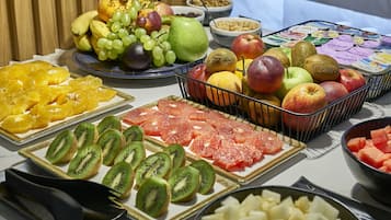 Verschillende soorten fruit en groenten, zoals kiwi, sinaasappels en appels, op een tafel gerangschikt.