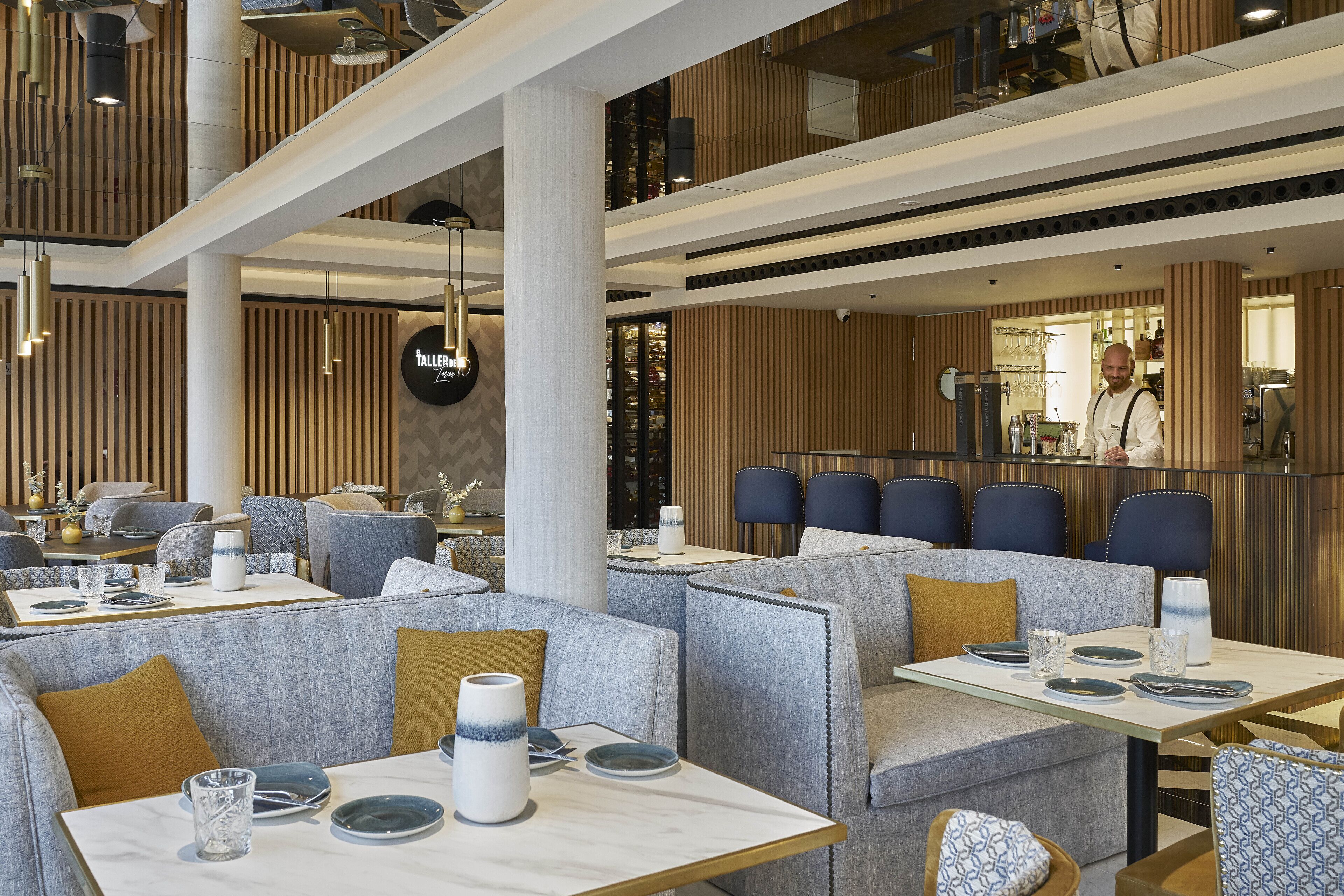 A modern restaurant with high ceilings, exposed wooden beams, and a mix of seating options including booths and tables.