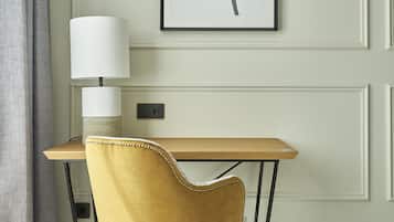 Una habitación con un escritorio de madera, una silla amarilla, una lámpara y un cuadro abstracto enmarcado en la pared.