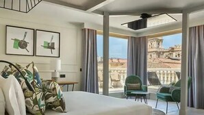 A modern hotel room with a large bed, a desk, and a balcony with a view of historic architecture. - Hotel Vincci Larios Diez (Málaga)