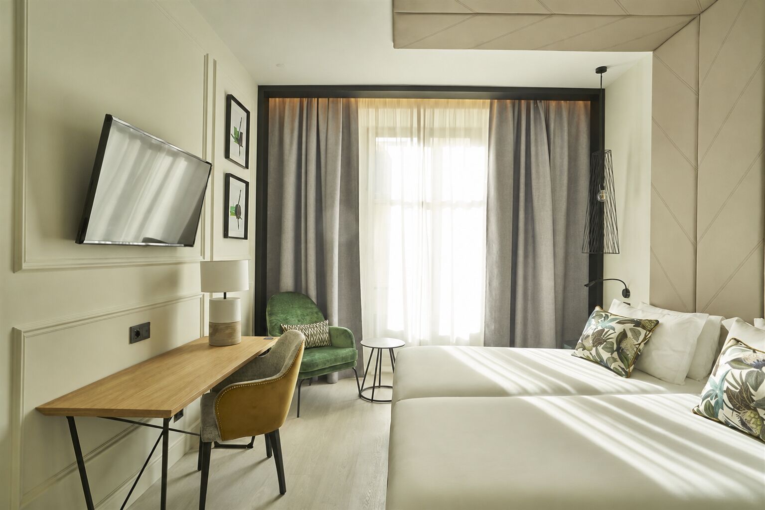 A hotel room with a bed, a desk, a chair, a TV, and a window with curtains.