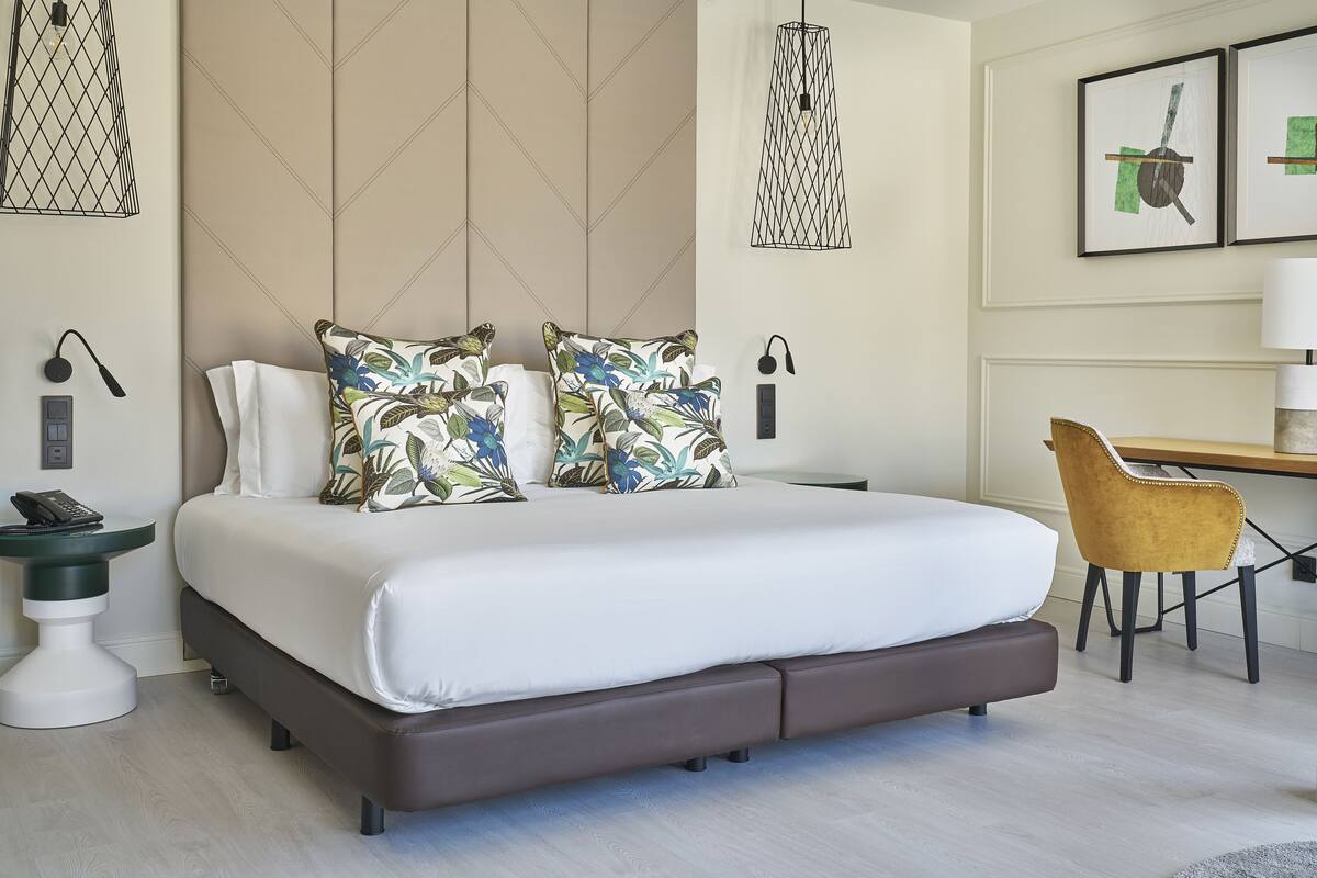 A modern bedroom with a large bed, a desk, and a chair.