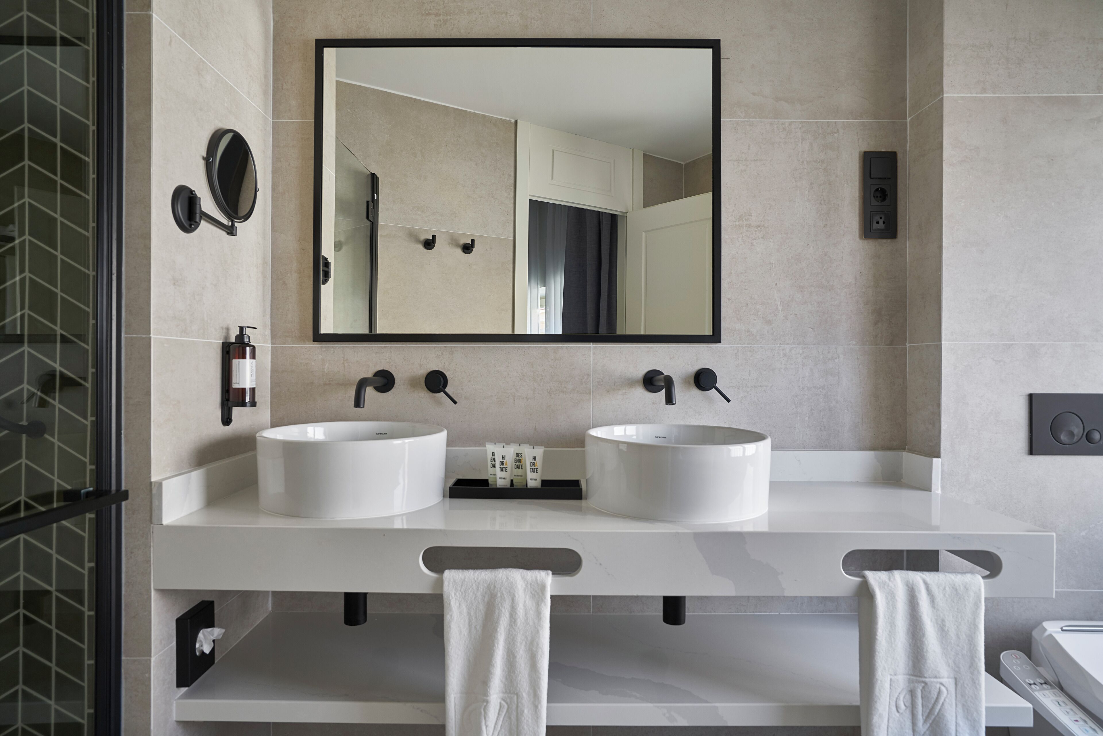 Un baño moderno con dos lavamanos, un espejo grande y un perchero para toallas.