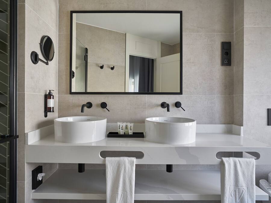 A modern bathroom with two sinks, a large mirror, and a towel rack.