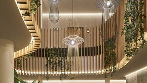 A modern interior with a central staircase, multiple hanging light fixtures, and indoor plants. - Hotel Vincci Larios Diez (Málaga)