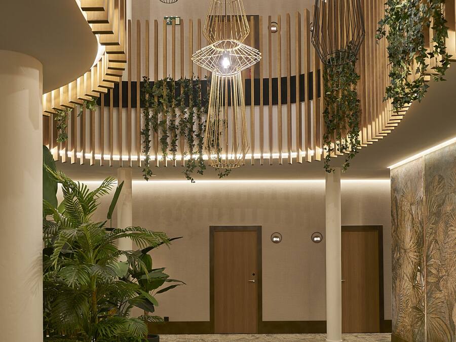 A modern interior with a central staircase, multiple hanging light fixtures, and indoor plants.