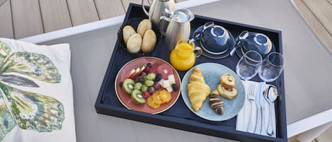 A tray with breakfast items including croissants, fruit, and a coffee pot.