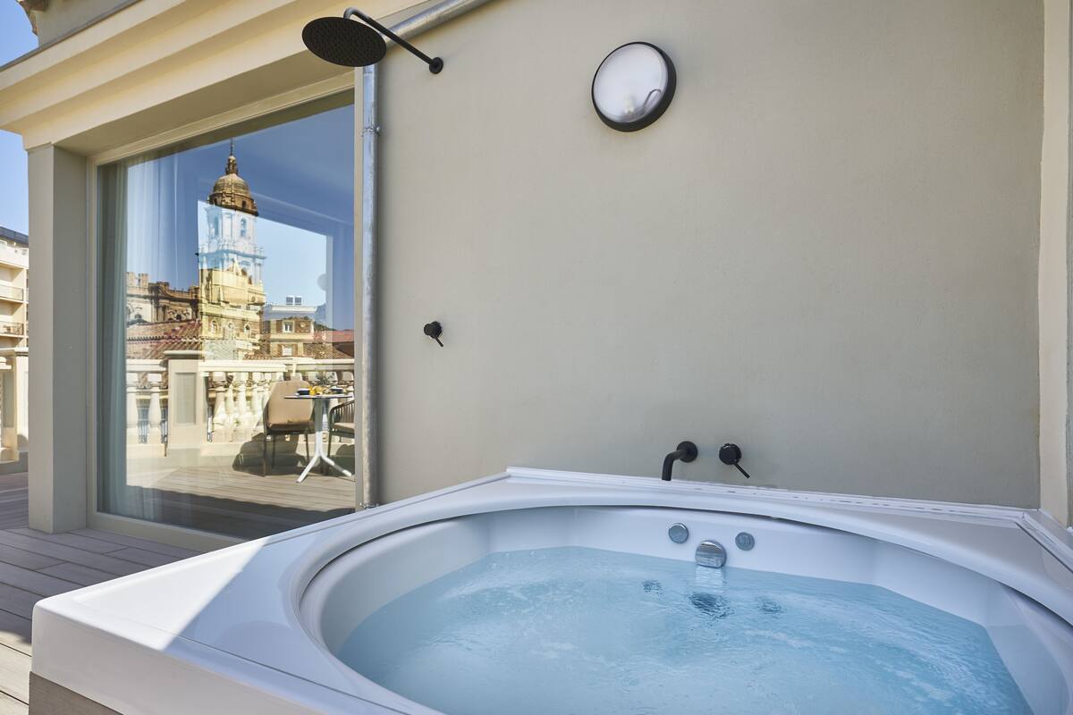 A hot tub on a balcony with a view of a cityscape and a building with a dome.