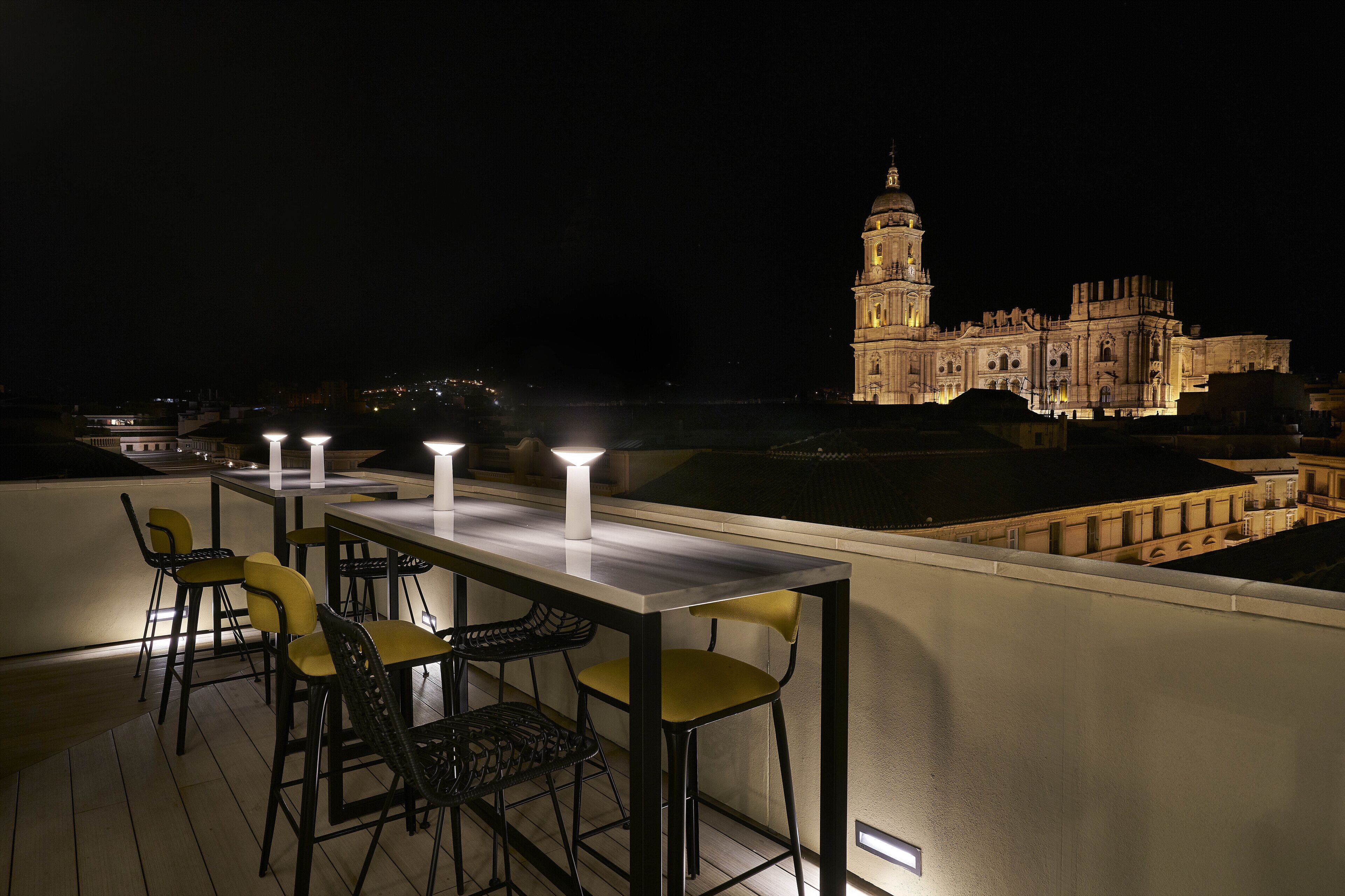 Terraza en la azotea con una mesa y sillas para comer, con vistas a un edificio histórico que tiene una torre destacada.