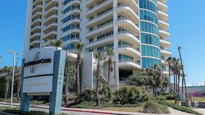 Un hotel de varios pisos con balcones, un letrero que dice 'The Ocean Club Villas at Ocean Club', y un frente de vidrio curvo.