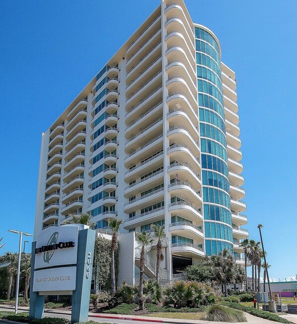 A multi-story hotel with a curved facade, balconies, and a sign indicating 'Villas at Ocean Club'.