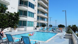 Un hotel con zona de piscina, varios balcones y un cielo azul despejado.
