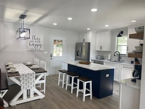 Enjoy meals at the central island with bar stools or dine at the table with white chairs.