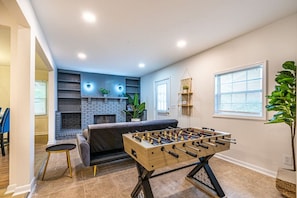 Un salón acogedor con mesa de fútbol, chimenea y sofá.