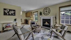 A living room with a fireplace, a world map on the wall, and a clock. - Charming Modern Victorian in the Village of EVL (Ellicottville)