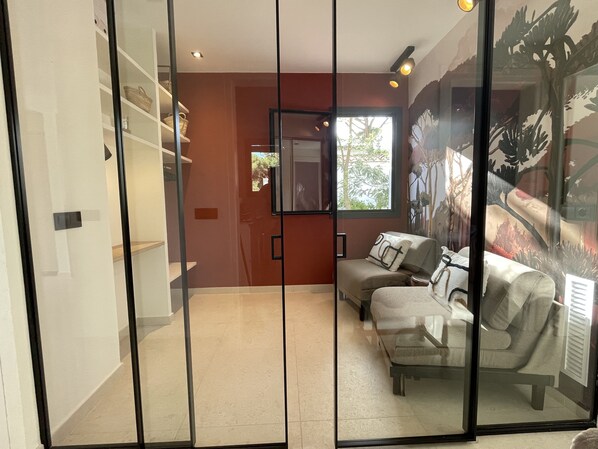 A modern living room with a sofa, a glass partition, and a mural on the wall. - Charming Spanish house with heated pool, 15 min walk from the beach (Calella de Palafrugell)