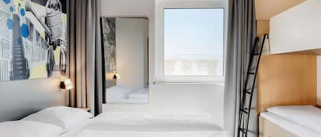 A hotel room with two beds, a large window, a mirror, and a wall with a cityscape artwork.