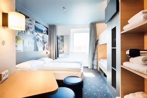 Une chambre d’hôtel comprenant un lit, un bureau, une chaise, une télévision et une armoire.