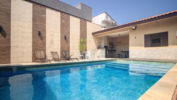 A swimming pool with lounge chairs and a patio area. - Piscina Aquecida, Ar Condicionado, Área Gourmet, Bilhar (Itanhaém)
