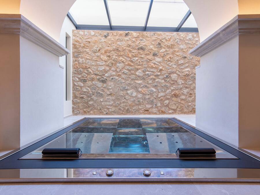Un intérieur moderne avec un mur en pierre, une table en verre et une verrière.