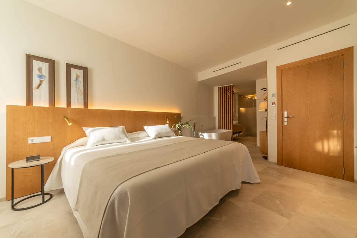 Een moderne hotelkamer met een groot bed, een nachtkastje en een houten hoofdeinde.