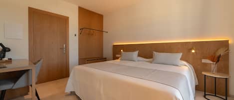 A modern hotel room with a large bed, a desk, and a chair.