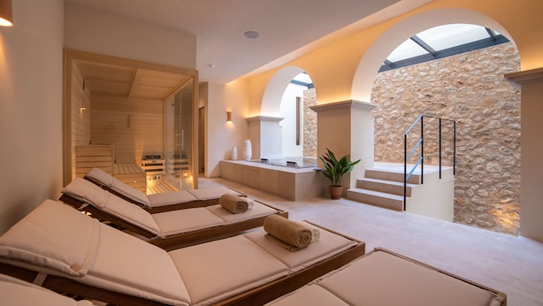 Un área de spa con tumbonas, una pared de piedra y una escalera.