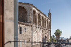 Stunning historic building with a series of arches and a bell tower, featuring a traditional tiled roof and a palm tree.