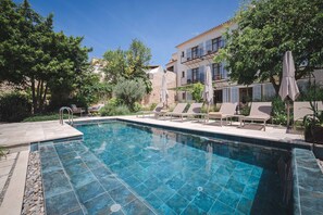 Relax by the serene pool surrounded by lush greenery and comfortable lounge chairs.