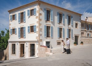 Traditional building with a symmetrical design and central entrance, featuring evenly spaced windows and potted plants on the ground level.