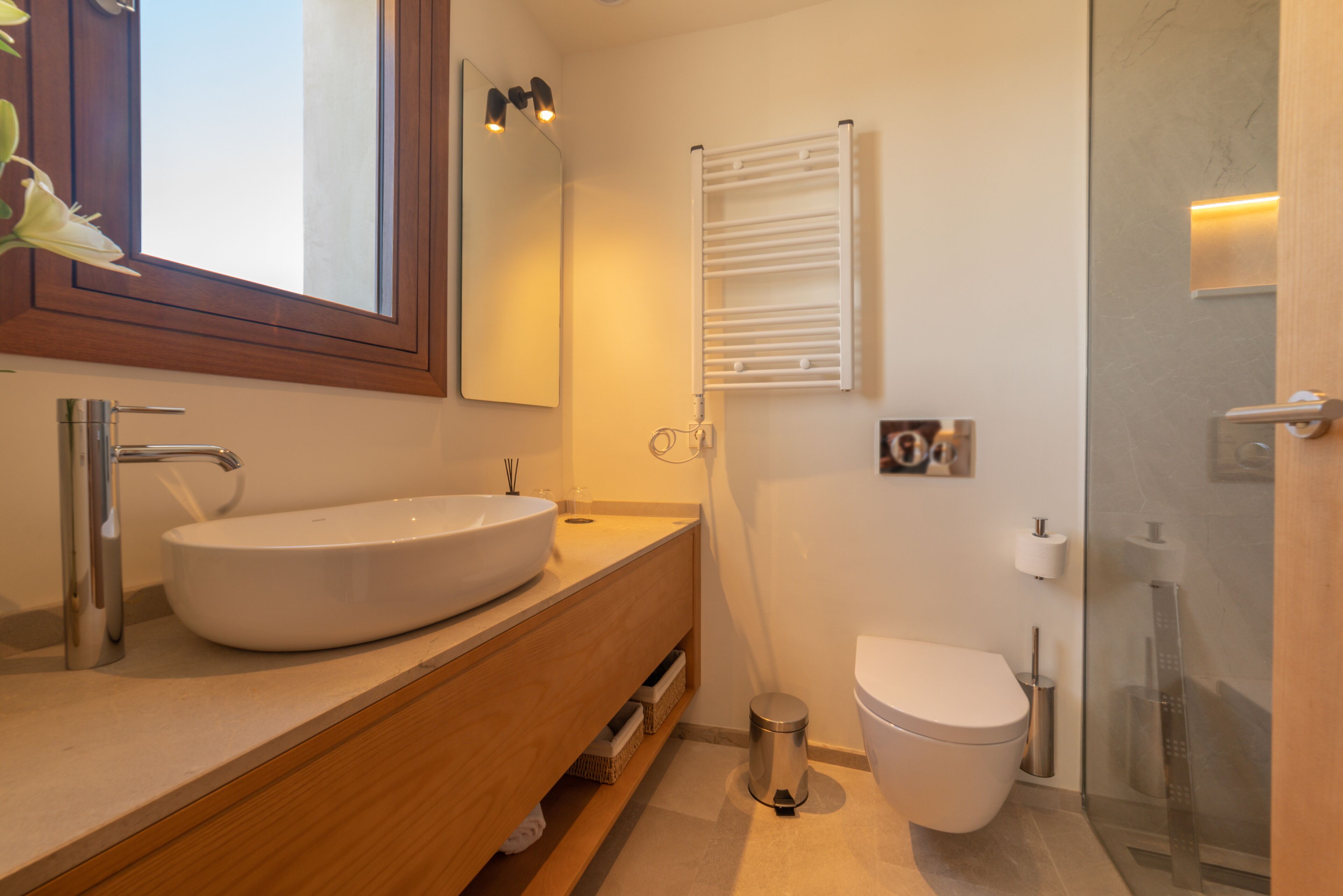 Un baño moderno con un lavamanos grande, un espejo, un inodoro y una ducha.