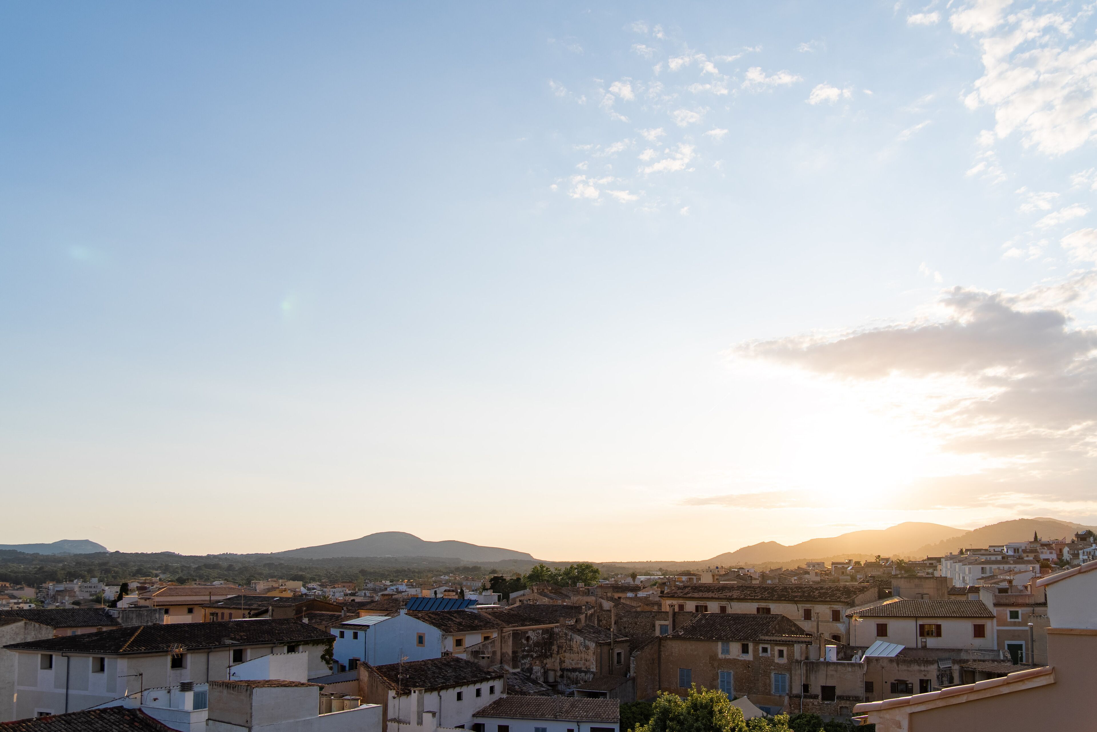 A view of a town with buildings and mountains in the background.