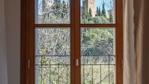 Una habitación con un amplio ventanal que da a un castillo y árboles.