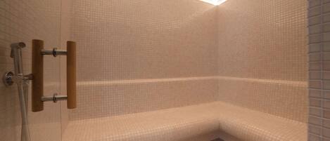 A corner shower with a bench, tiled walls, and a curved ceiling.