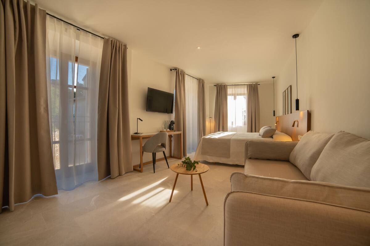 Een moderne hotelkamer met een bed, bank, bureau en televisie.